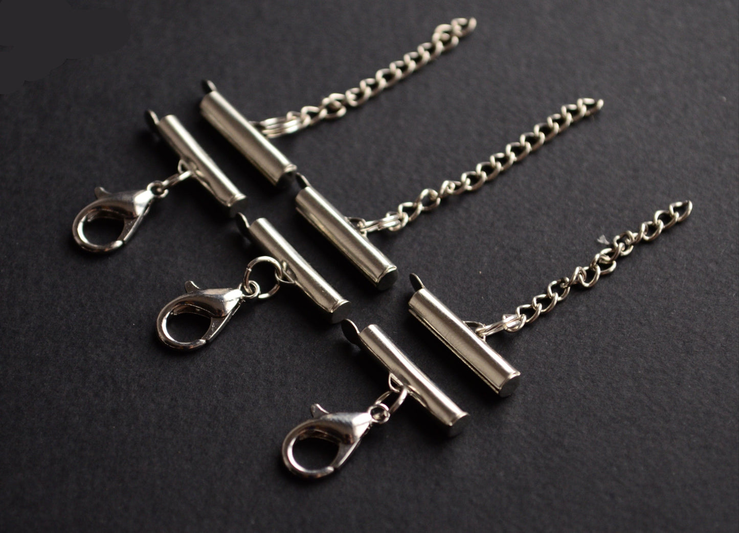 Silver necklace clasps and chains on a black background